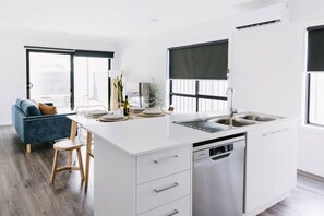 A modern kitchen with a central island, white cabinetry, and a built-in dishwasher. - King Bed, 3 Beds, 2 bath + Sleeps 6 (Sale)