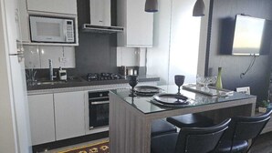 Uma cozinha compacta com micro-ondas, fogão e luminárias pendentes modernas.