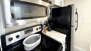 Cocina compacta con microondas, estufa y refrigerador.