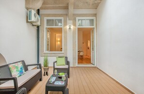 Ein Balkon mit Korbmöbeln, einem kleinen Tisch und einem Blumentopf.