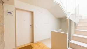 A modern interior with a wooden floor, a white door labeled 'AL,' and a staircase with white railings. - Clérigos Tower - Experience in Porto (Porto)