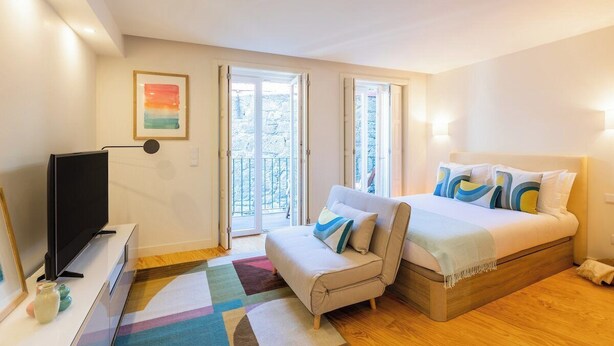 A bedroom with a bed, a TV, a sofa, and a balcony. - Clérigos Tower - Experience in Porto (Porto)