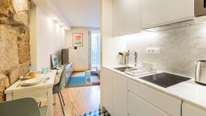 A modern kitchen with white cabinets, a black induction cooktop, and a stainless steel kettle. - Clérigos Tower - Experience in Porto (Porto)