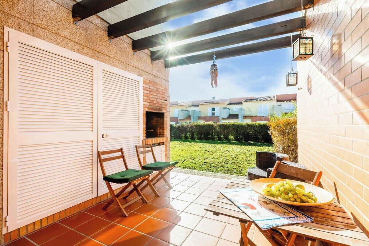 Une terrasse avec une table, des chaises et un barbecue.