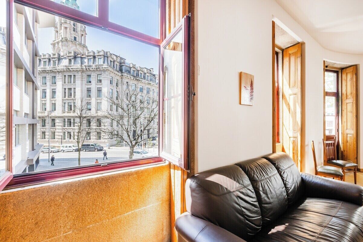 Habitació amb una finestra gran, un sofà de cuir i una porta de fusta.