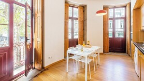 Un comedor con una mesa y sillas blancas, puertas de madera y vistas al exterior.