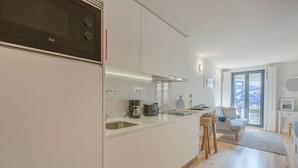 Eine moderne Küche mit weißen Schränken, einem eingebauten Ofen und einer Kaffeemaschine.