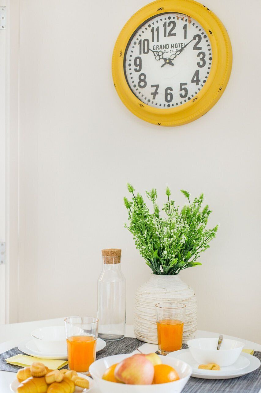 A dining table with plates, glasses, and a clock.