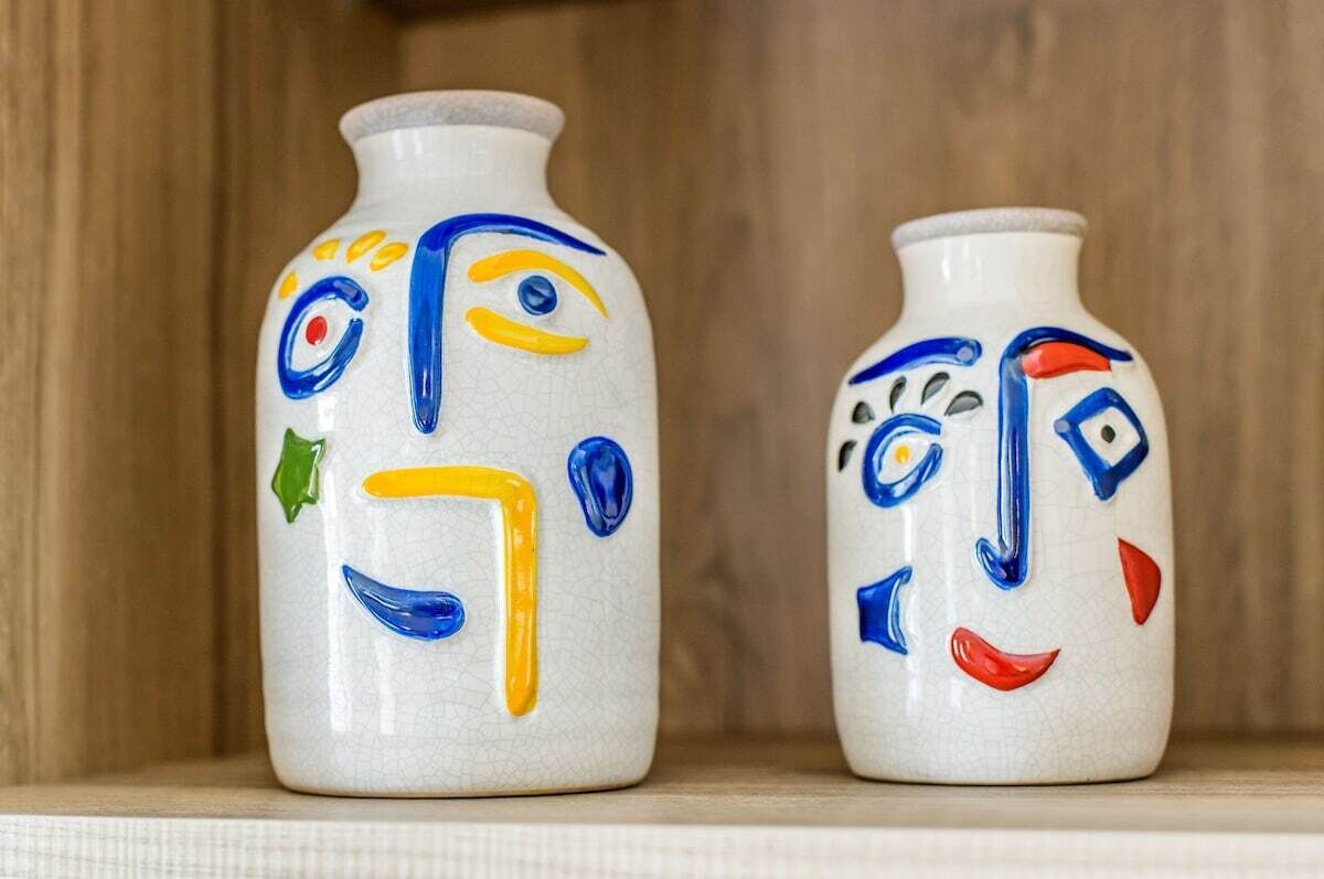 Two ceramic vases with abstract designs on a shelf.