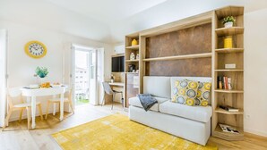 En moderne stue med sofa, spisebord og reol.