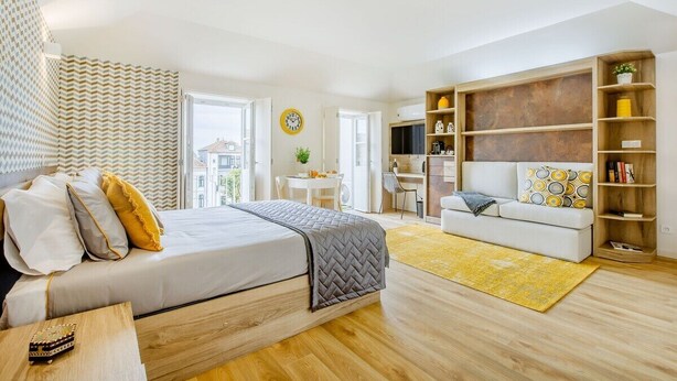 Et moderne soveværelse med seng, sofa, skrivebord og bogreol.