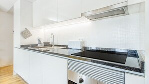 Et moderne køkken med hvide skabe, en sort bordplade, en indbygget komfur og et emfang i rustfrit stål.