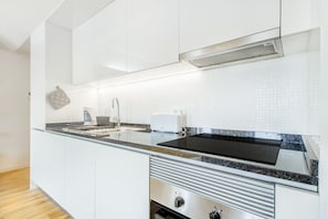 Eine moderne Küche mit weißen Schränken, einer schwarzen Arbeitsplatte, einem eingebauten Herd und einer Edelstahl-Dunstabzugshaube.