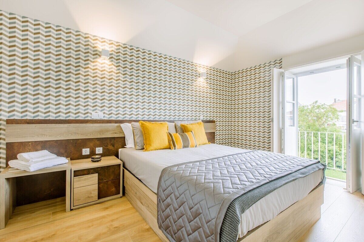 Ein Schlafzimmer mit Bett, Nachttischen, einem Holzkopfende und einem Balkon mit Geländer.