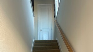 A carpeted staircase with a wooden handrail leading to a white door at the top. - Cozy 1-bedroom studio above detached garage in serene Yountville (Yountville)