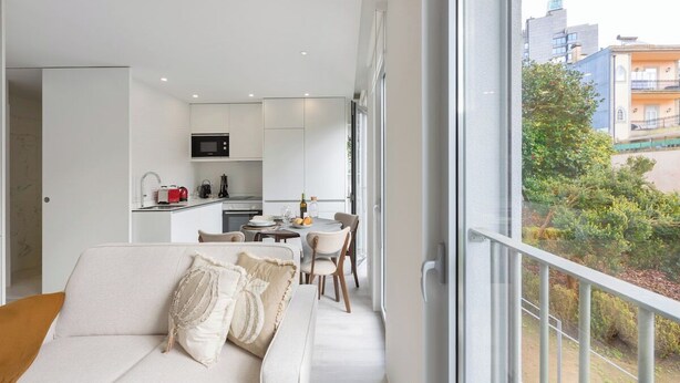 Eine moderne Wohnung mit Wohnbereich, Küchenzeile und einem Balkon mit Blick auf die Stadt.