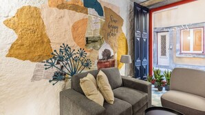 Ein gemütliches Zimmer mit einem grauen Sofa, einem kleinen Tisch und einer Wand, die mit einer Karte und Text verziert ist.