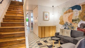 Ein modernes Wohnzimmer mit Schachbrettparkett, einer Holztreppe und einem Wandgemälde.