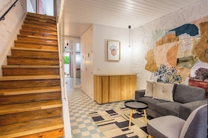 Ein modernes Wohnzimmer mit Schachbrettparkett, einer Holztreppe und einem Wandgemälde.