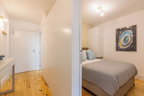 Ein Schlafzimmer mit einem Bett, einem Nachttisch, einem Spiegel und einer Wanduhr.