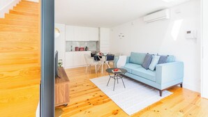 Un appartement moderne avec un escalier en bois, un canapé bleu clair, un coin repas et une cuisine.