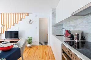 Eine moderne Küche mit Marmorarbeitsplatte, einer roten Kaffeemaschine und einem eingebauten Backofen.