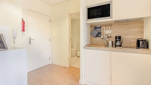 A modern kitchen with white cabinetry, a microwave, a coffee maker, and a hanging towel rack. - Trindade Modern Flat (with Air Conditioning) (Porto)