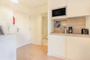 A modern kitchen with white cabinetry, a microwave, a coffee maker, and a hanging towel rack. - Trindade Modern Flat (with Air Conditioning) (Porto)