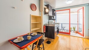 Een compacte keuken met een eettafel gedekt voor twee personen, een klein wandrek en een rode deuroplossing die naar een buitenruimte leidt, compleet met een tafel en stoelen.