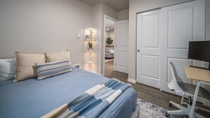 Um quarto moderno com uma cama, uma escrivaninha e uma televisão.