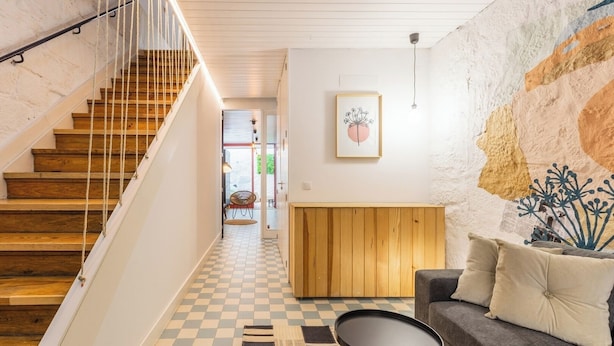 A staircase with wooden steps and a white railing, leading to a room with a checkered floor, a sofa, and a small table. - Victoria Studios 4 @ Clérigos (Porto)