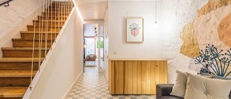 Eine Treppe mit Holzhäuschen und einem weißen Geländer, die zu einem Raum mit Schachbrettfußboden, einer Couch und einem kleinen Tisch führt.