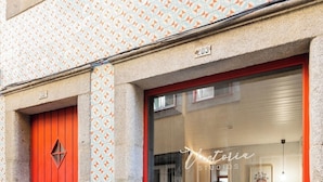 A building with a red door and a large glass window displaying a sign that reads "Victoria Studios." - Victoria Studios 4 @ Clérigos (Porto)