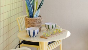 A dining area with a table, chairs, a potted plant, and a framed artwork on the wall. - São Félix Ocean Views | 1BR & Terrace (São Félix da Marinha)