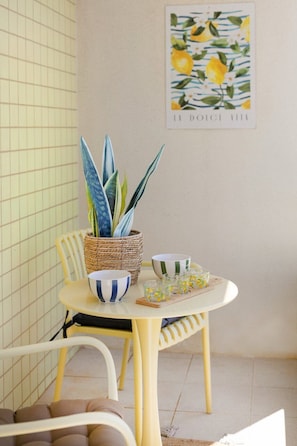 Uma sala de jantar com uma mesa, cadeiras, uma planta em vaso e uma obra de arte emoldurada na parede.