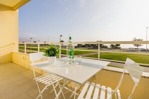 Ein Balkon mit einem weißen Tisch und Stühlen, einer Chivas-Flasche und einem Blumentopf.