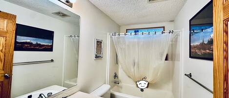 A bathroom with a sink, mirror, toilet, and bathtub.