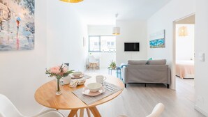 Ein stilvolles Wohnzimmer mit einem grauen Sofa, einem Esstisch mit Blumen in einer Vase und einem Gemälde an der Wand.