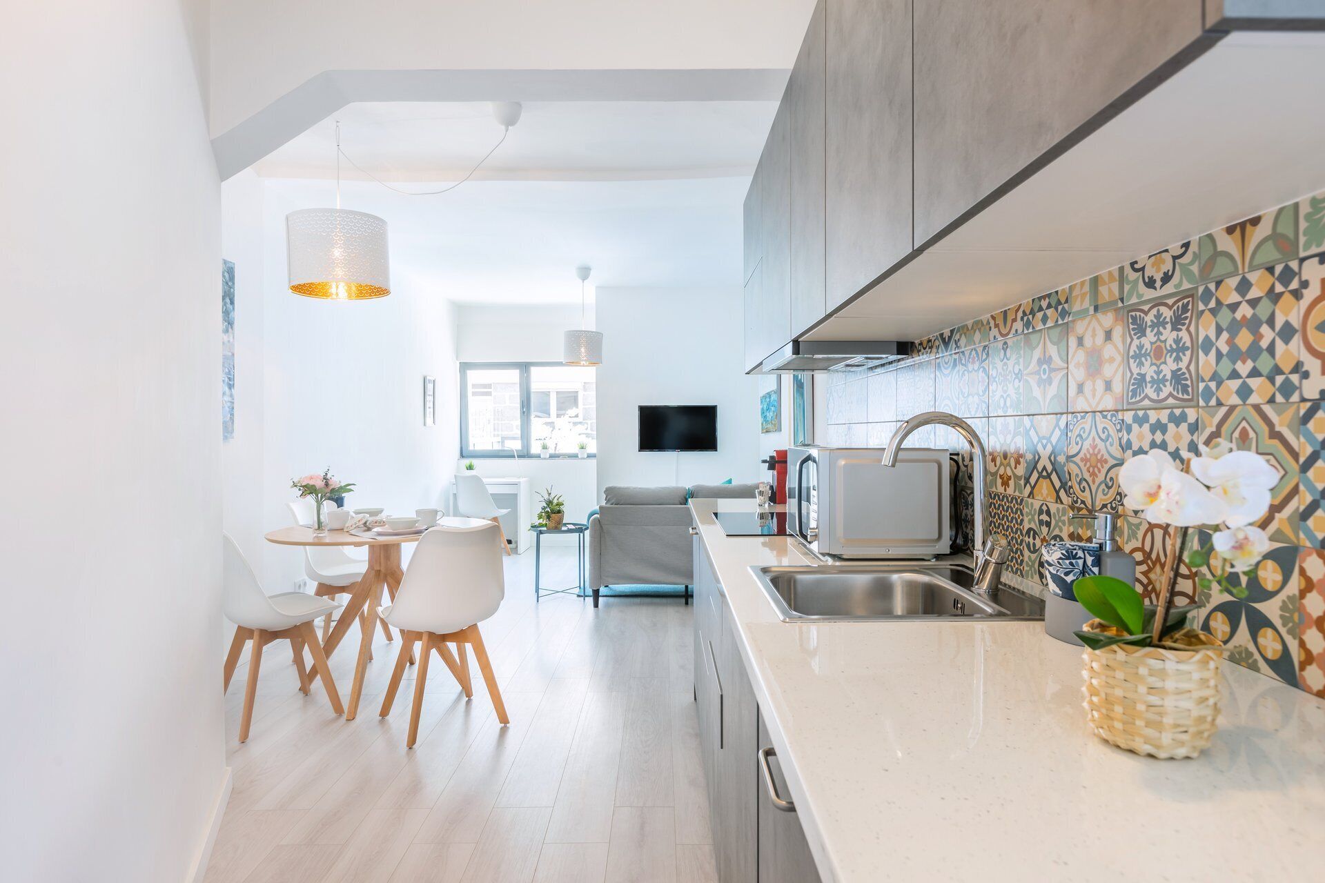 A modern kitchen with a microwave, sink, and decorative tiles.