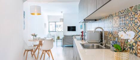 A modern kitchen with a microwave, sink, and decorative tiles.