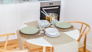 A dining table set with plates, glasses, and cutlery, surrounded by chairs. - Heroismo Duplex Terrace III (Porto)