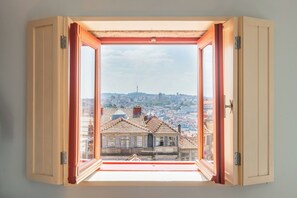 A room with a large window offering a view of a cityscape, including a prominent tower. - Victoria Studios 8 @ Clérigos (Porto)
