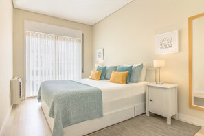 A bedroom with a bed, bedside tables, a window with blinds, and wall art. - Santa Catarina Modern Flat (Porto)