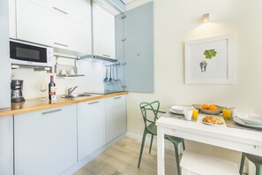 A modern kitchen with a microwave, sink, and dining area with a table set for breakfast. - Santa Catarina Modern Flat (Porto)
