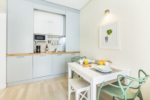 A modern kitchen with a microwave, coffee maker, and a dining area with a table and chairs. - Santa Catarina Modern Flat (Porto)