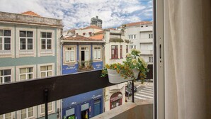 Ein Balkon mit Blick auf Gebäude, einem hängenden Blumentopf und eine Straße darunter.