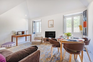 Ein Wohnzimmer mit Sofa, Couchtisch, Fernseher, Kamin und einem Essbereich mit Stühlen und Tisch.