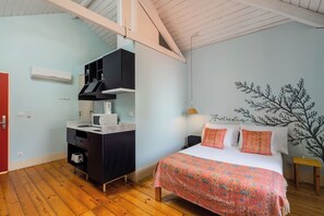 Ein Schlafzimmer mit Bett, Nachttisch, Schreibtisch mit Stuhl, Kleiderschrank und einer Wand-Klimaanlage.