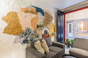 Ein gemütliches Zimmer mit einem grauen Sofa, einem kleinen Tisch und einer Wand, die mit einer Karte und Text verziert ist.