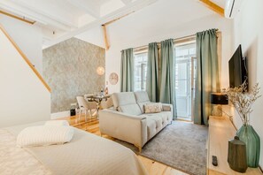 A modern hotel room with a sofa, a bed, a desk, and a television. - Santa Catarina Charming Loft (Porto)